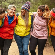 Diverse group of five women standing arm in arm as they hike a nature trail