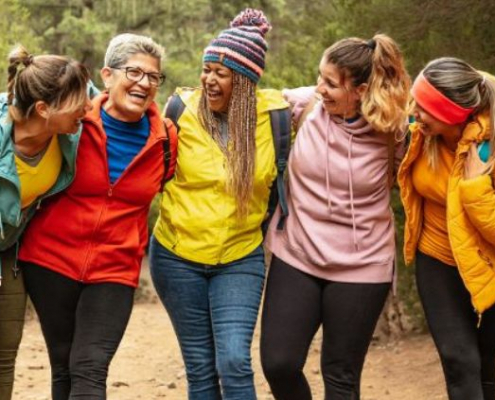 Diverse group of five women standing arm in arm as they hike a nature trail